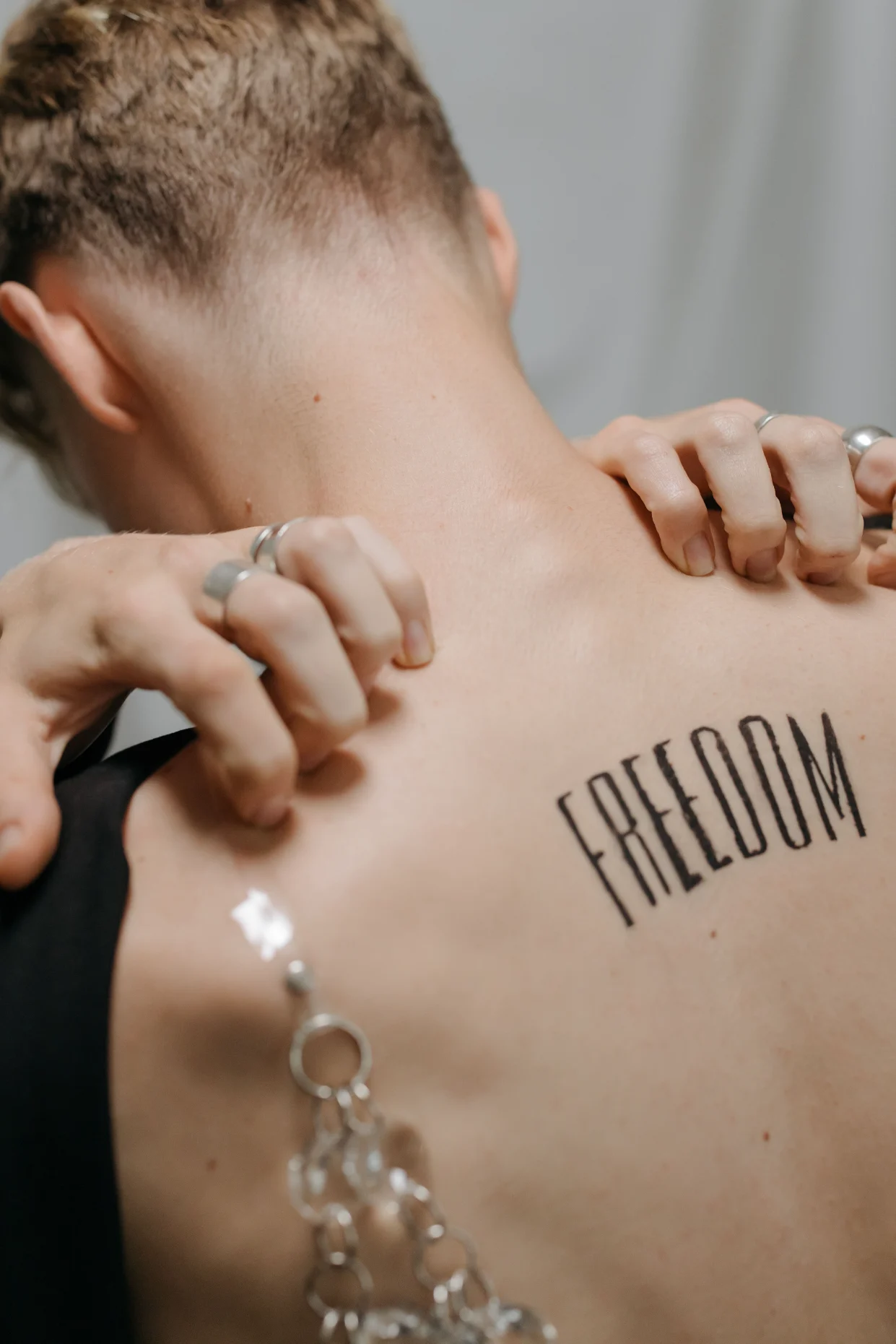 Bare back with a chain and freedom tattoo
